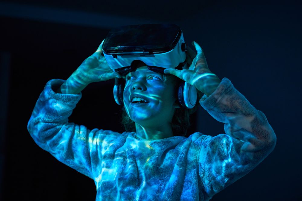 Excited child taking off VR goggles and looking away