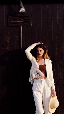 A long hair fashion model with a hat at the beach with a dark background