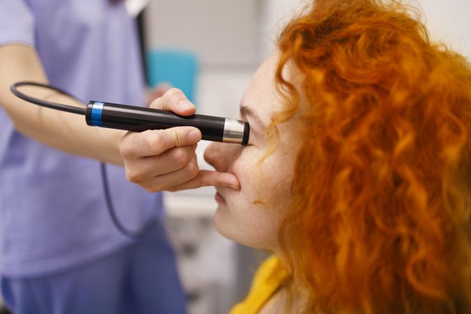 Red haired woman in clinic with medical device checking her eye