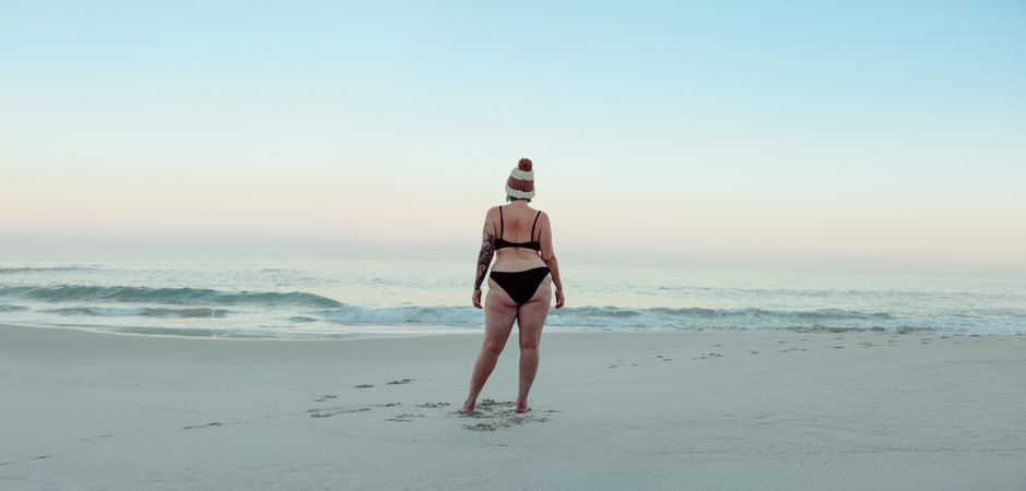 Anonymous female winter bather standing at the beach in swimwear