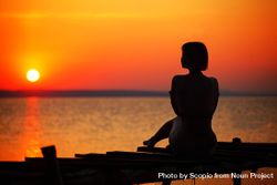 Silhouette of woman sitting on dock during sunset 0J6mr0