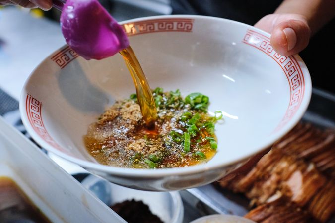 Crop person pouring sauce into bowl