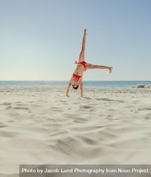 Acrobatic woman upside down with both hands on ground and legs in air 5nln2b