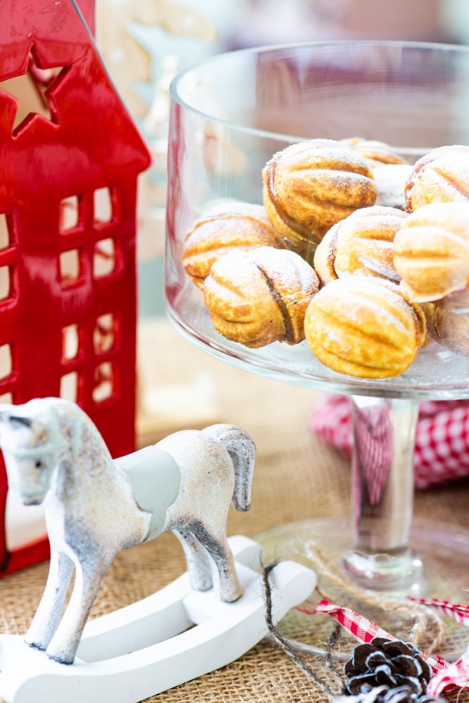 Holiday dessert concept with walnut shaped cookies stuffed with caramel cream surrounded next to horse toy decorations