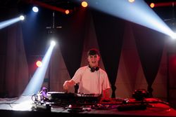 Young man in the headphones play music at the disco