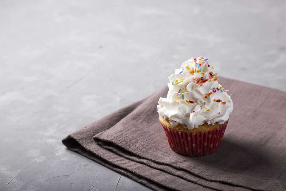 Tasty party cupcakes on the table. Cupcakes with whipped cream.