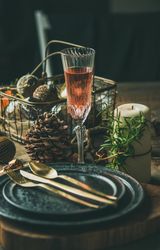 Table setting with crystal flute of Champagne, pinecone, and candle
