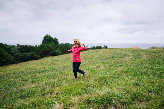 Cheerful woman enjoying countryside landscape stretching hands