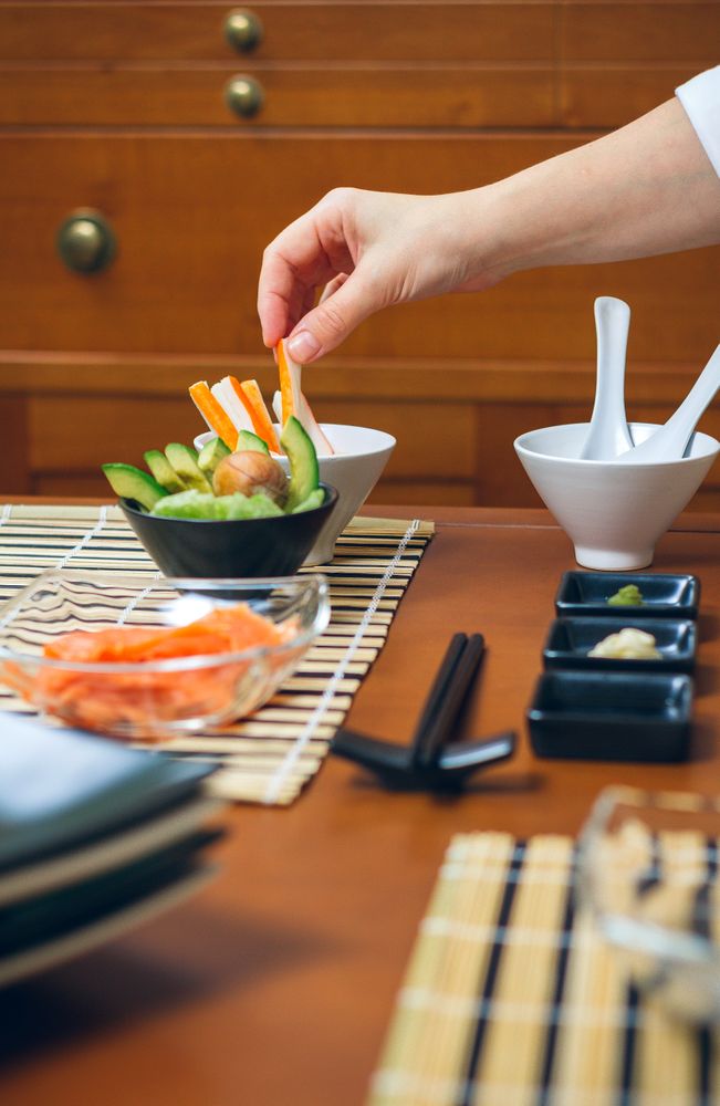 Chef hand taking a crab stick from bowl prepared to make sushi