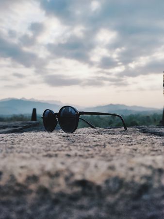 Sunglasses Resting on a Stone Wall with Mountain and Sky Background: A Serene Landscape