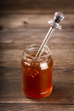 Honey in glass jar on the table.