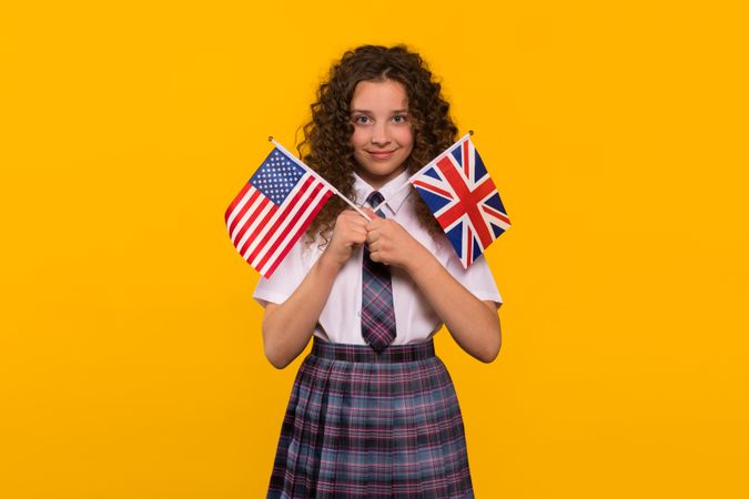 Smiling girl holding both USA and UK flags