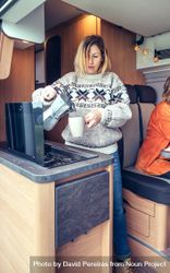 Women in warm sweater pouring coffee from moka in back of van, vertical 4Mm1r4