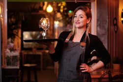 Cheerful waitress holding tray with wineglasses
