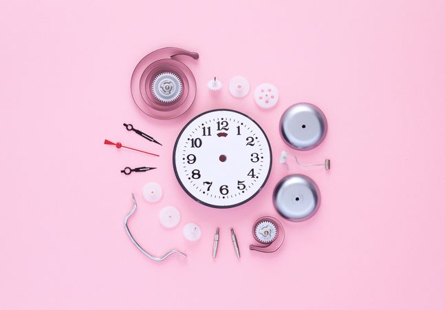 Clock components organized in a circle over pink background