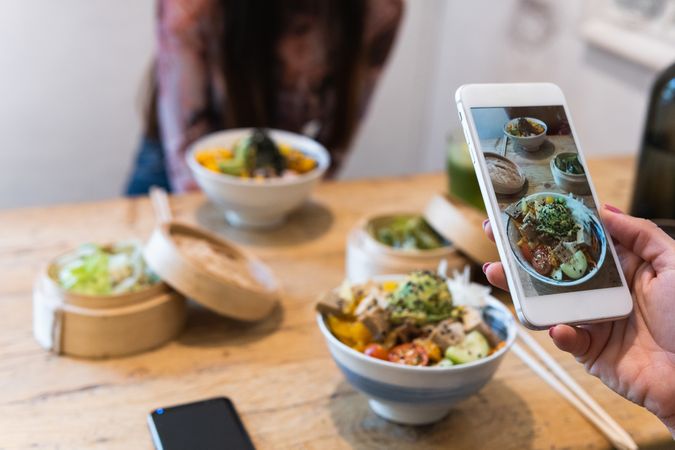 Anonymous woman taking photo of dish in restaurant