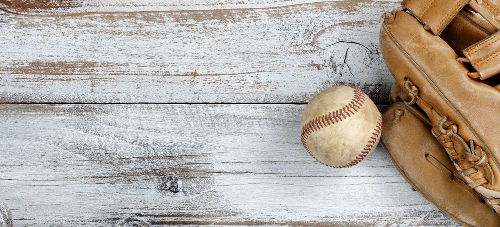Flat lay view of old baseball and mitt on rustic wooden boards