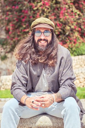 Smiling man sitting on stone border