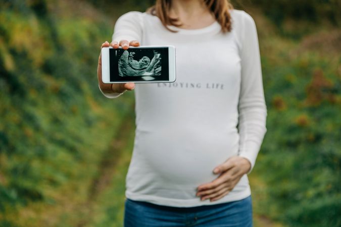 Pregnant woman showing ultrasound on the mobile