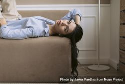 Wide view of young woman lying on a couch with her hair hanging down the side 0WOgP0