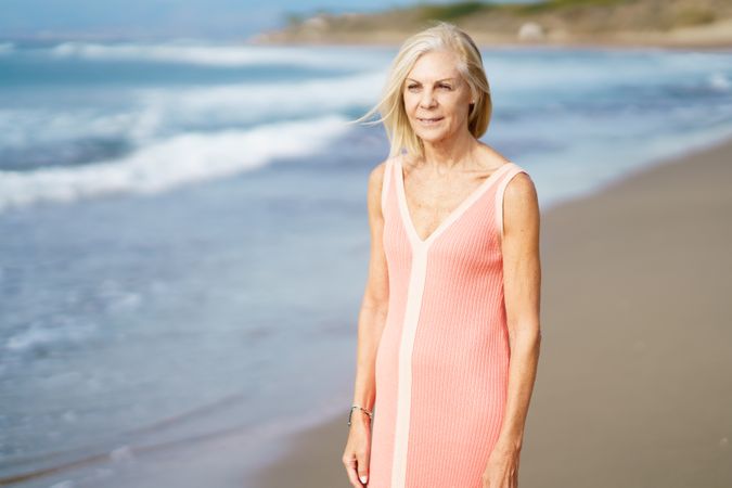 Calm mature woman smiling while standing in the sand on a beach