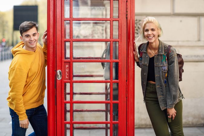 Male and female posing on different sides of a phone booth