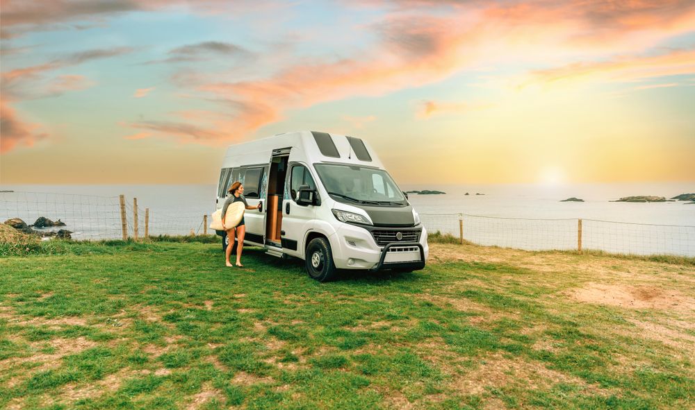 Female walking with surfboard outside of motorhome