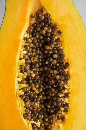 Halved ripe papaya with seeds on table