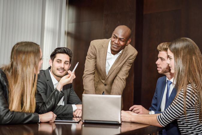 Black man in business attire leading his colleagues in a brain storming meeting at work