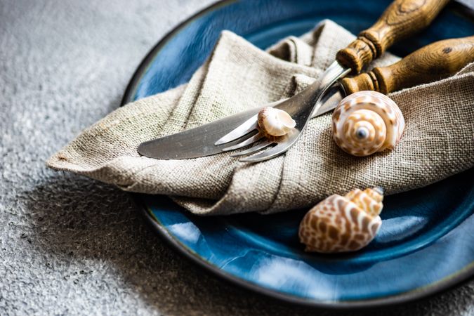 Marine themed table setting with shells on grey concrete background with copy space
