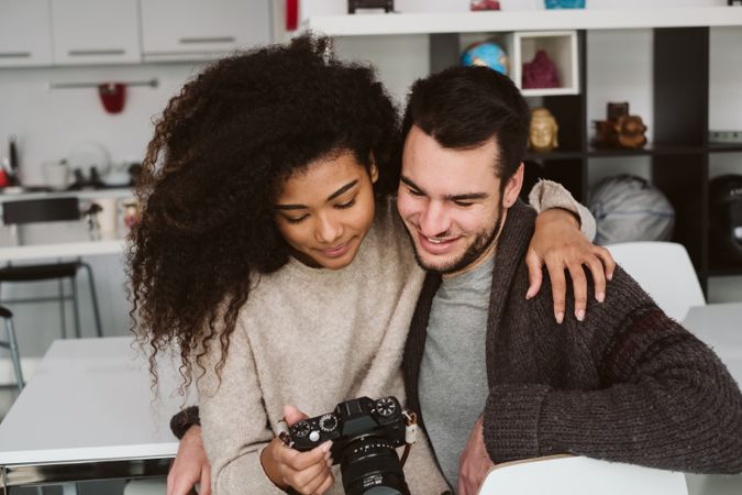 Multiracial couple looking at photo camera at home