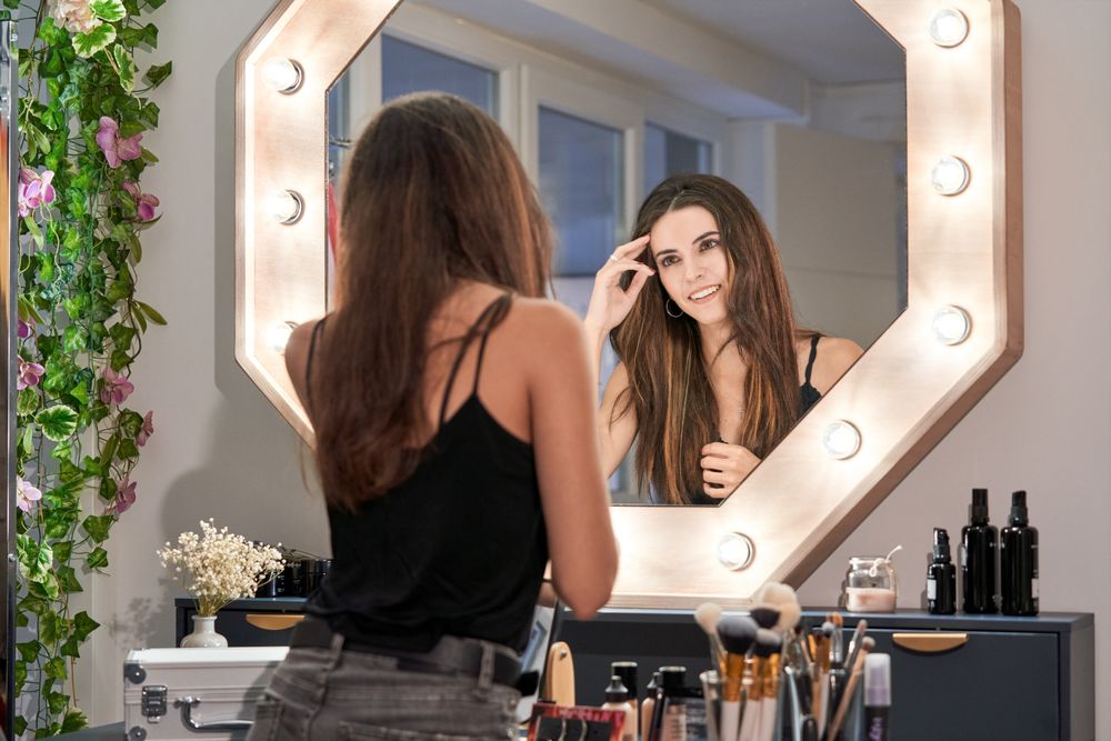 Brunette woman looking in makeup mirror