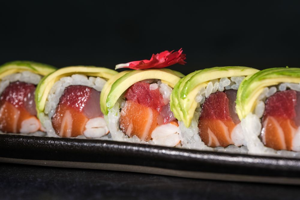 Delicious sushi rolls with avocado slices served on tray