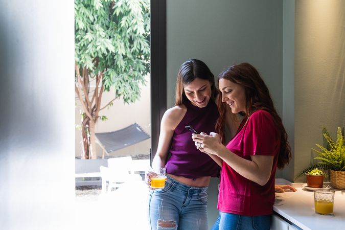 Content women browsing smartphone and enjoying orange juice