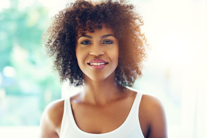 Portrait of confident female with curly hair on leafy background