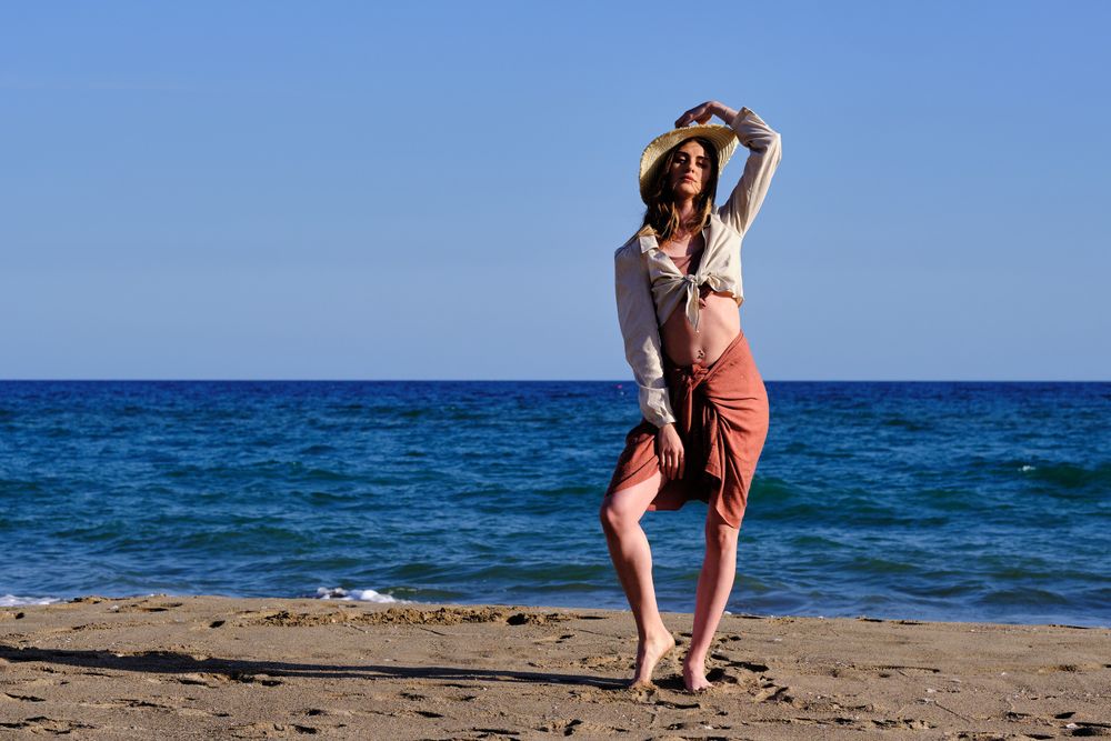 A fashion model with a hat at the beach before sunset