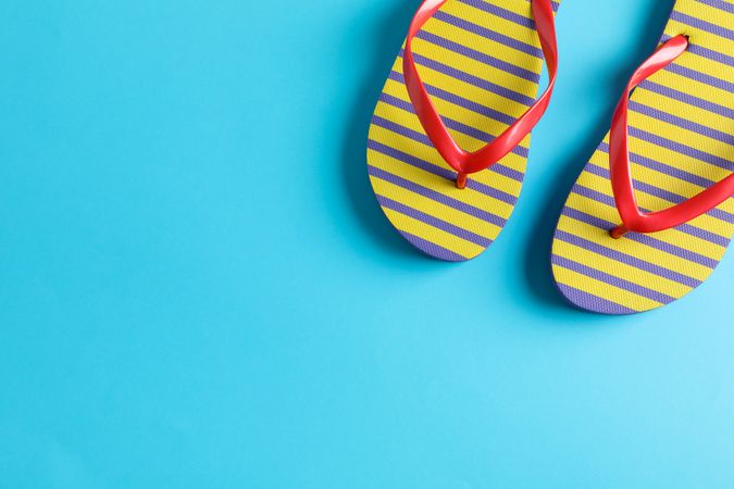 Flip flops on color background, space for text. Summer vacation backdrop