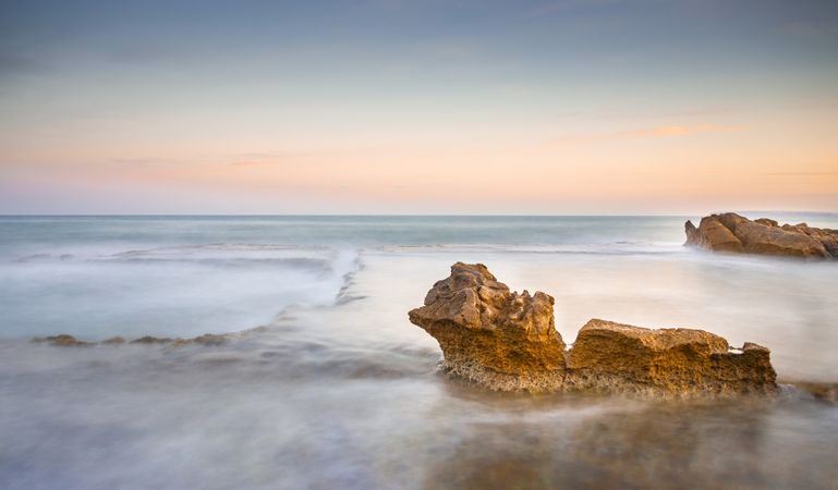 Amazing stones on shore near water and blue sky