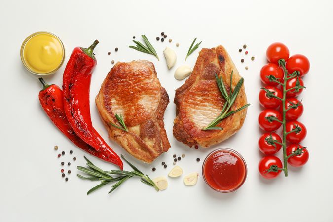 Vegetables and fried steaks on light background, top view