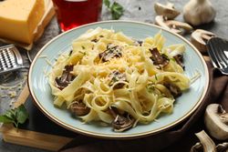 Composition with plate of tasty pasta and ingredients for cooking on gray background