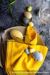 Easter table setting with pastel eggs and yellow napkin 4Zeajx