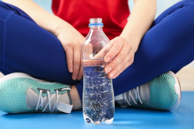 Person sitting crossed legs with plastic water bottle