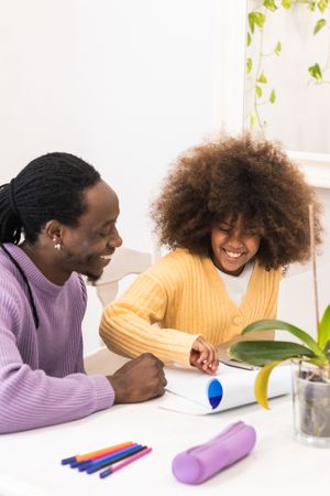 Black father helping daughter with homework on laptop