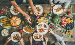 Group of people serving food over festive side dishes and turkey