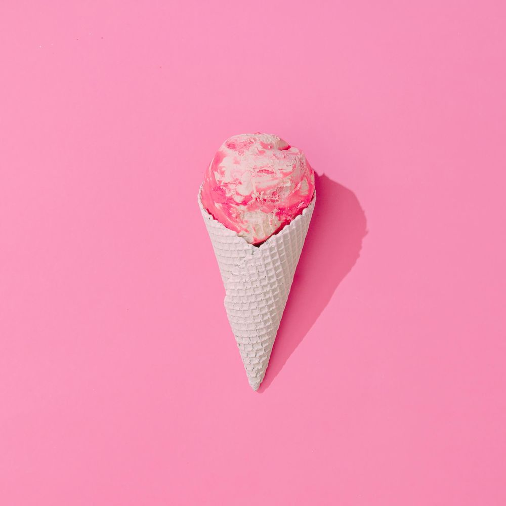 Waffle cone of pink ice cream on pink background