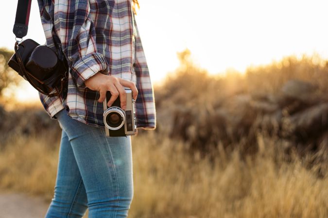 Unrecognizable woman taking photos with analog camera in the countryside