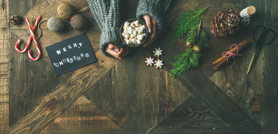 Homely holiday with “Merry Christmas” card, woman and hot chocolate, copy space
