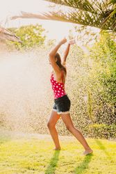 Cheerful teenager having fun with jet of water