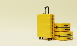 Three yellow hard shell roller suitcases on light yellow background
