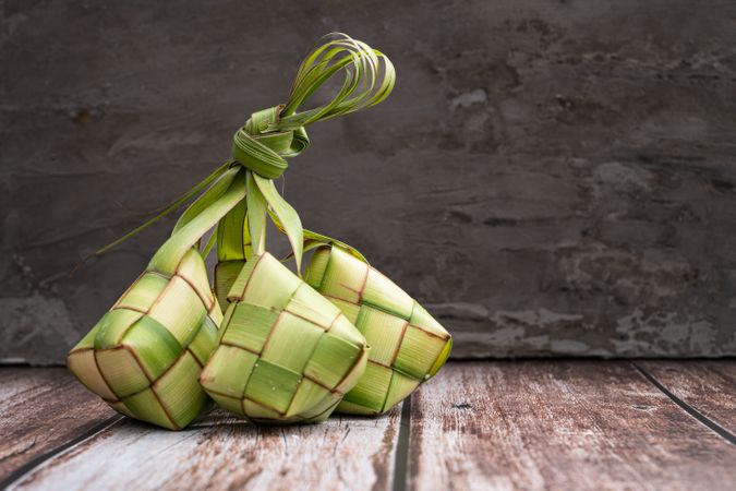 Uncooked ketupat filled with rice, placed on wooden surface